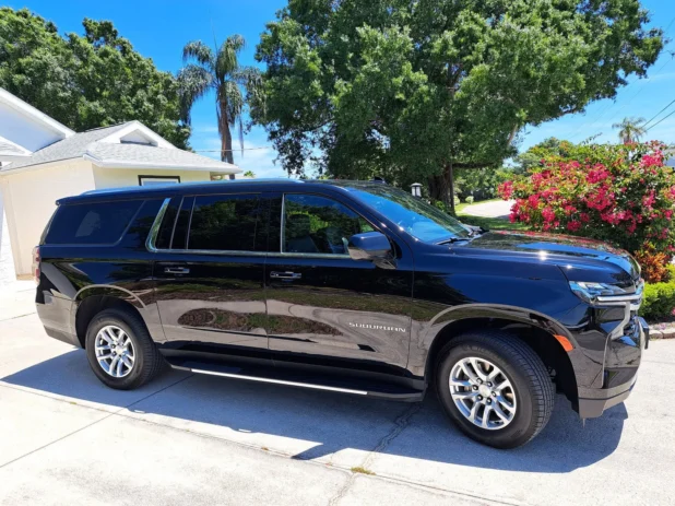 Black Suburban SUV parked beside driveway